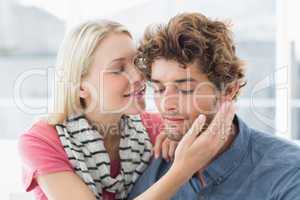 Woman about to kiss man on his cheek