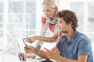 Casual couple using computer in bright office
