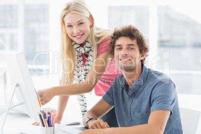 Casual couple using computer in bright office