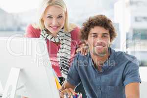 Smiling casual couple using computer in bright office