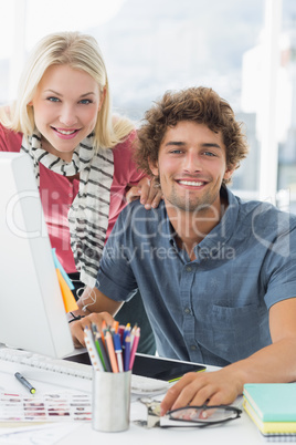 Smiling casual couple using computer in bright office