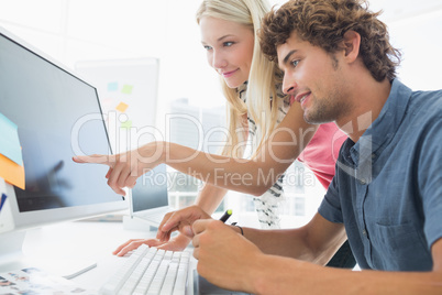 Casual couple using computer in office