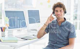Casual man with headset sitting by computers in office