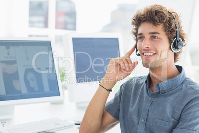 Smiling casual young man with headset in office