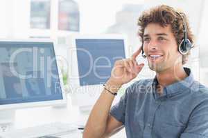 Smiling casual young man with headset in office