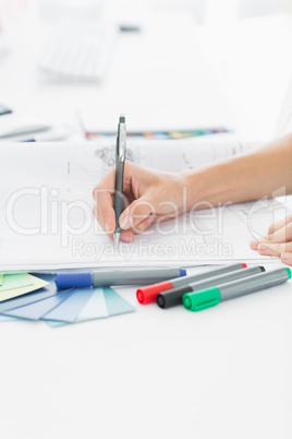 Artist drawing something on paper with pen at office