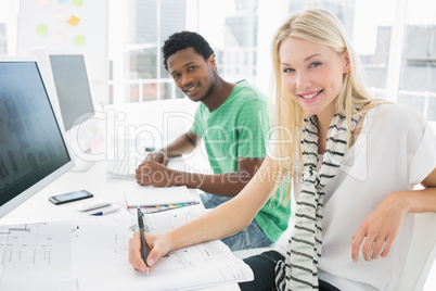 Artist drawing something on paper besides colleague at office