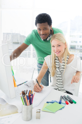 Artist drawing something on paper while using computer with coll
