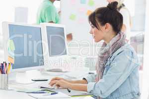 Artist using computer with colleagues behind at office