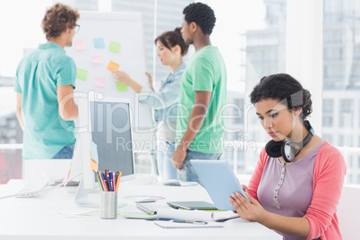 Woman using digital tablet with group of colleagues behind