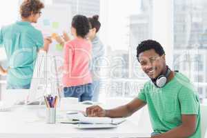 Casual man with group of colleagues behind in office