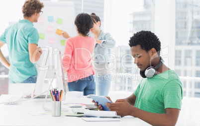 Casual man using digital tablet with colleagues behind in office