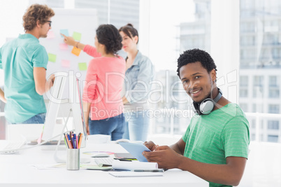 Casual man using digital tablet with colleagues behind in office