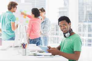 Casual man using digital tablet with colleagues behind in office