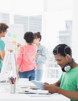 Casual man using digital tablet with colleagues behind in office