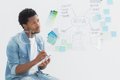 Thoughtful artist writing notes in front of whiteboard