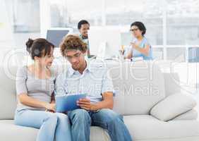 Casual couple using digital tablet with colleagues at creative o