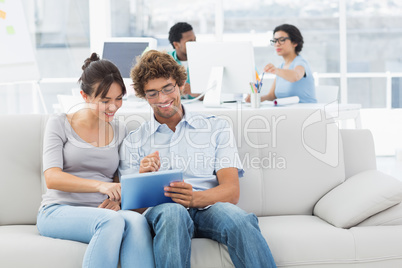 Couple using digital tablet with colleagues at creative office