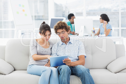 Couple using digital tablet with colleagues at creative office