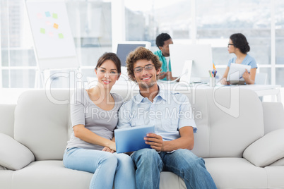 Couple using digital tablet with colleagues at creative office