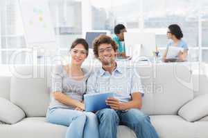 Couple using digital tablet with colleagues at creative office