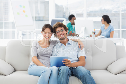 Couple using digital tablet with colleagues at creative office