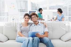 Couple using digital tablet with colleagues at creative office