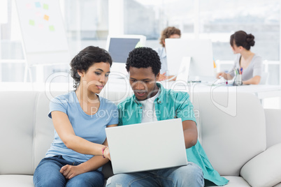 Couple using laptop with colleagues at creative office