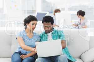 Couple using laptop with colleagues at creative office