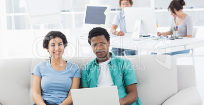 Couple using laptop with colleagues at creative office
