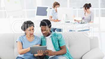 Couple using digital tablet with colleagues at creative office