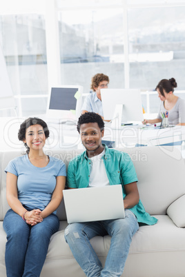 Couple using laptop with colleagues at creative office