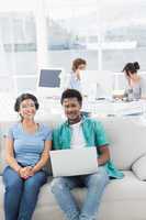 Couple using laptop with colleagues at creative office