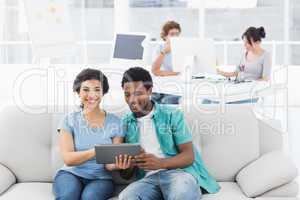 Couple using digital tablet with colleagues at creative office