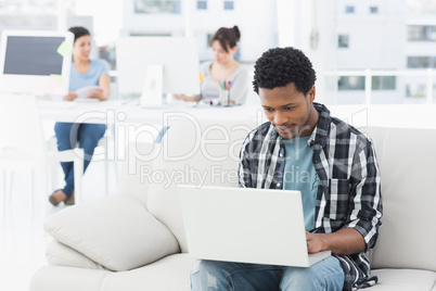 Man using laptop with colleagues at creative office