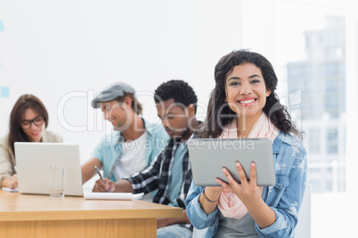 Woman using digital tablet with colleagues behind in office