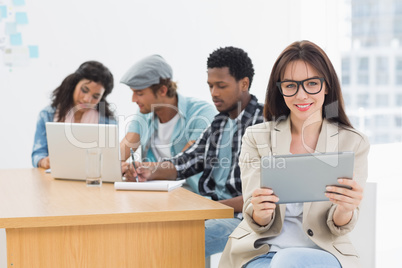 Woman using digital tablet with colleagues behind in office