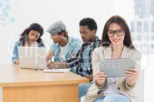 Woman using digital tablet with colleagues behind in office