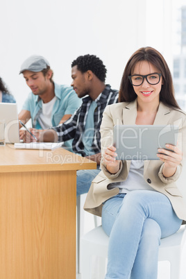 Woman using digital tablet with colleagues behind in office