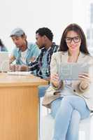 Woman using digital tablet with colleagues behind in office