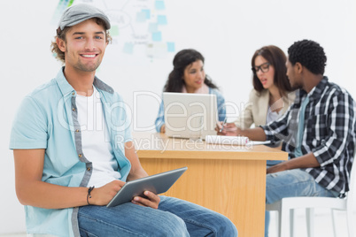 Man using digital tablet with colleagues behind in office