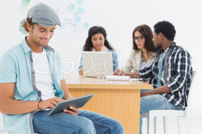 Man using digital tablet with colleagues behind in office