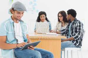 Man using digital tablet with colleagues behind in office