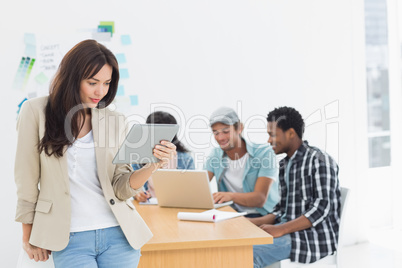 Woman using digital tablet with colleagues behind in office