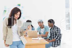 Woman using digital tablet with colleagues behind in office