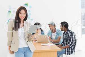 Woman using digital tablet with colleagues behind in office