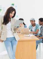 Woman using digital tablet with colleagues behind in office