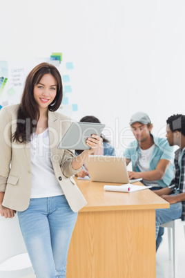 Woman using digital tablet with colleagues behind in office