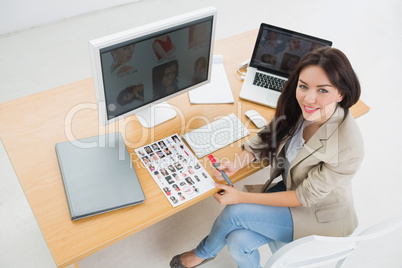Female artist sitting at desk with computers in office