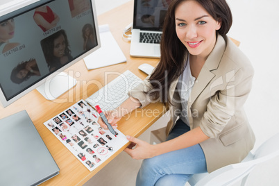 Female artist sitting at desk with computers in office